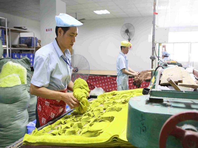 Factory worker cutting layers of plush fabric to pattern