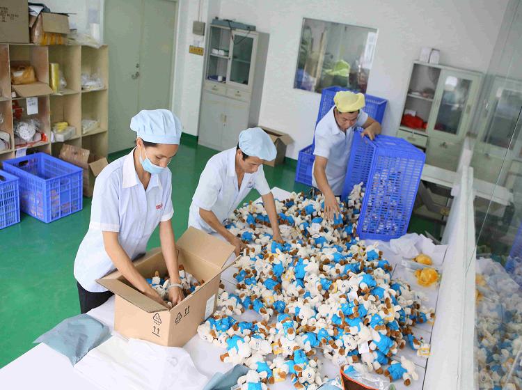 Workers packing finished plush toys into cartons at the packing table