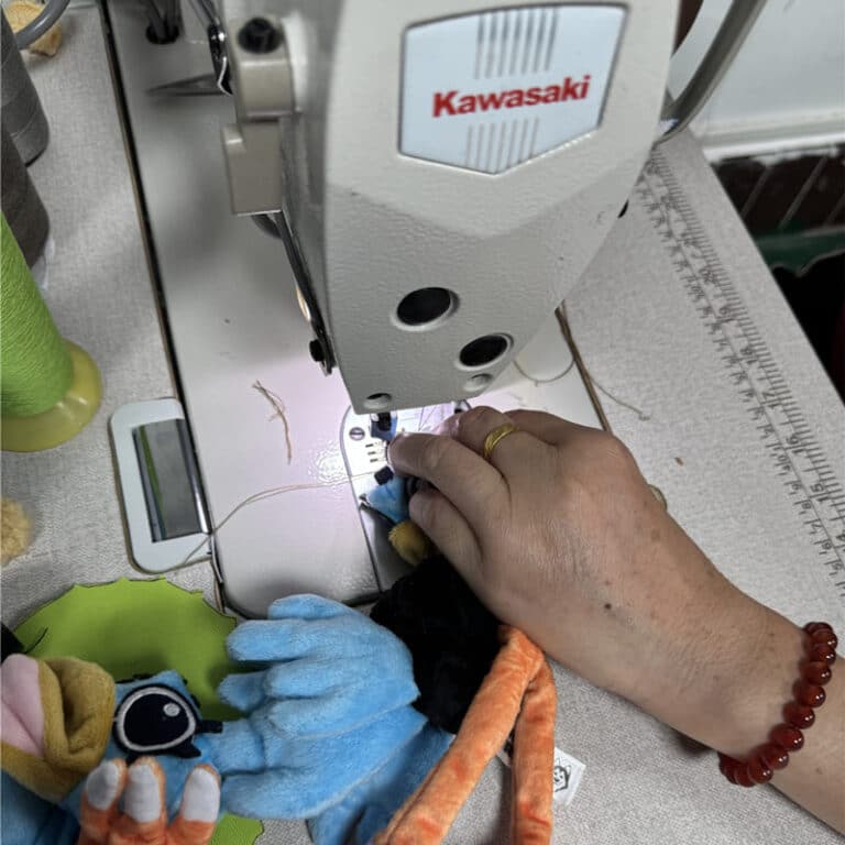 Worker's hands sewing plush toy parts on a Kawasaki industrial sewing machine