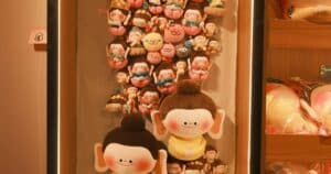 Vertical display of colorful custom plush toys arranged on a shelf, showing the variety produced by a Shenzhen plush manufacturing factory.